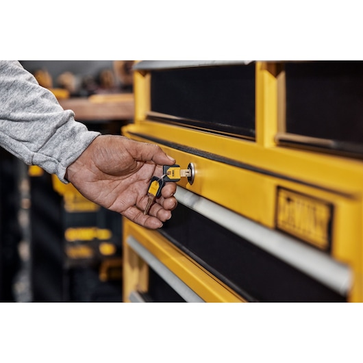 A Person Turning a Key In A DEWALT Cabinet